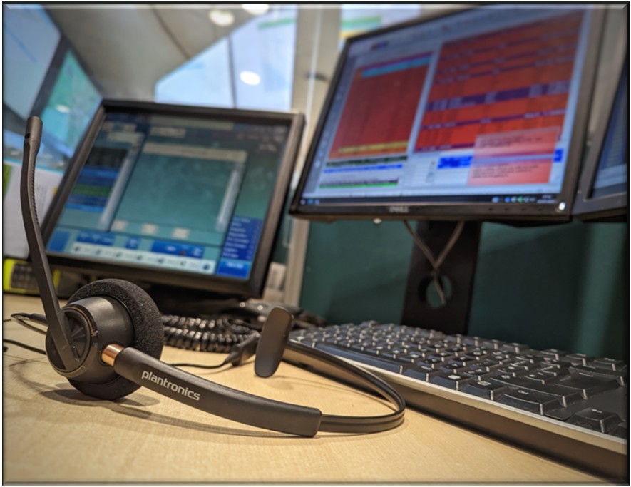 A telephone headset on a desk, with a computer in the background.