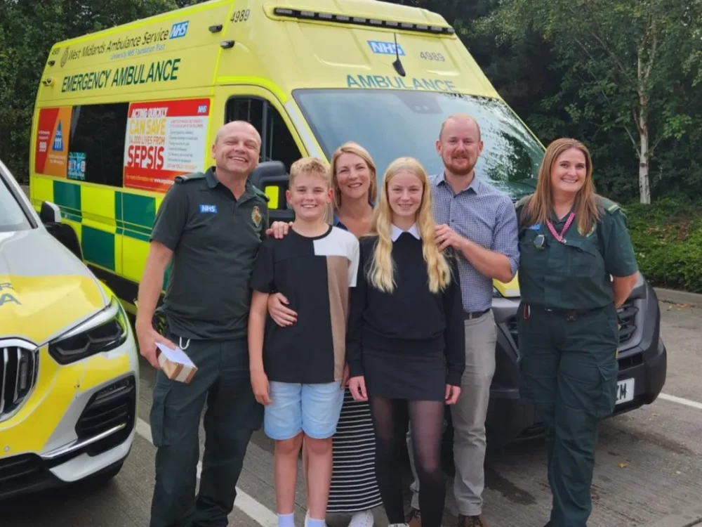 Family standing with ambulance crew in front of an ambulance