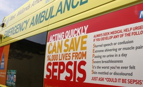 Photo of the side of an ambulance with a red sepsis poster on the side outlining the signs of sepsis