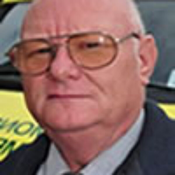 a man in tinted glasses in front the front of an ambulance