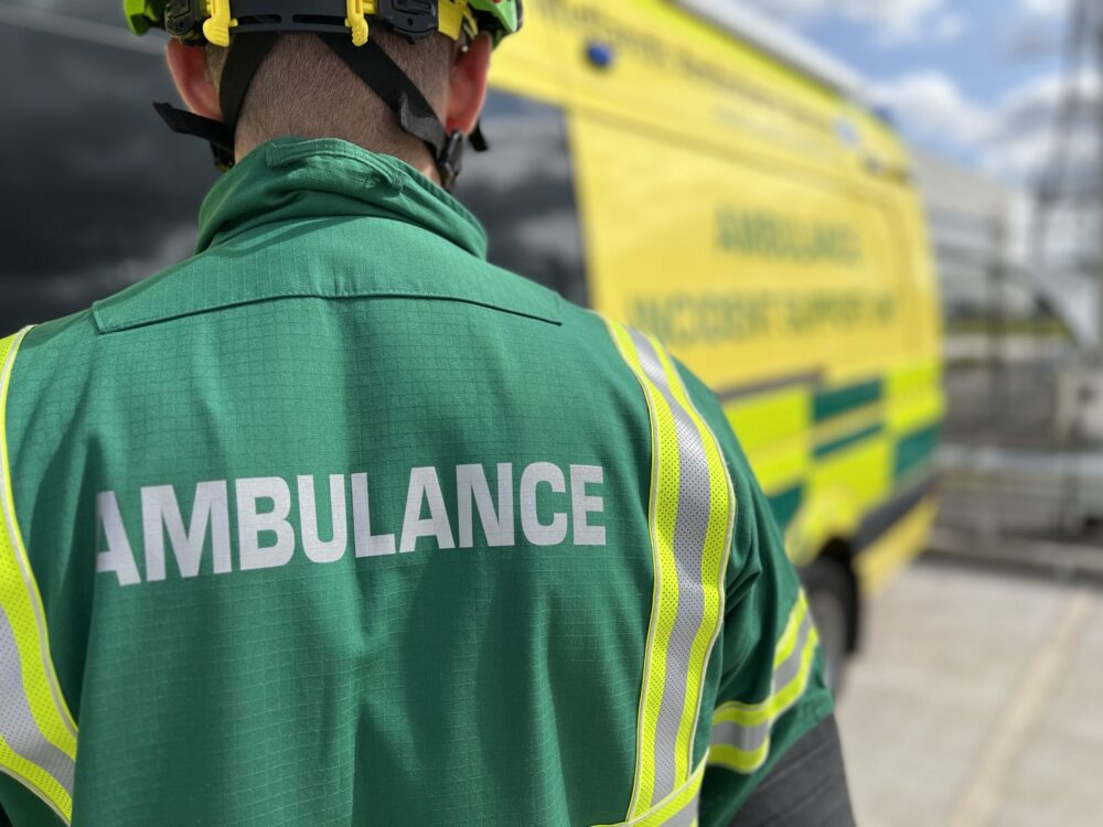 HART paramedic in helmet and green overalls with back to camera facing Incident Support Unit ambulance