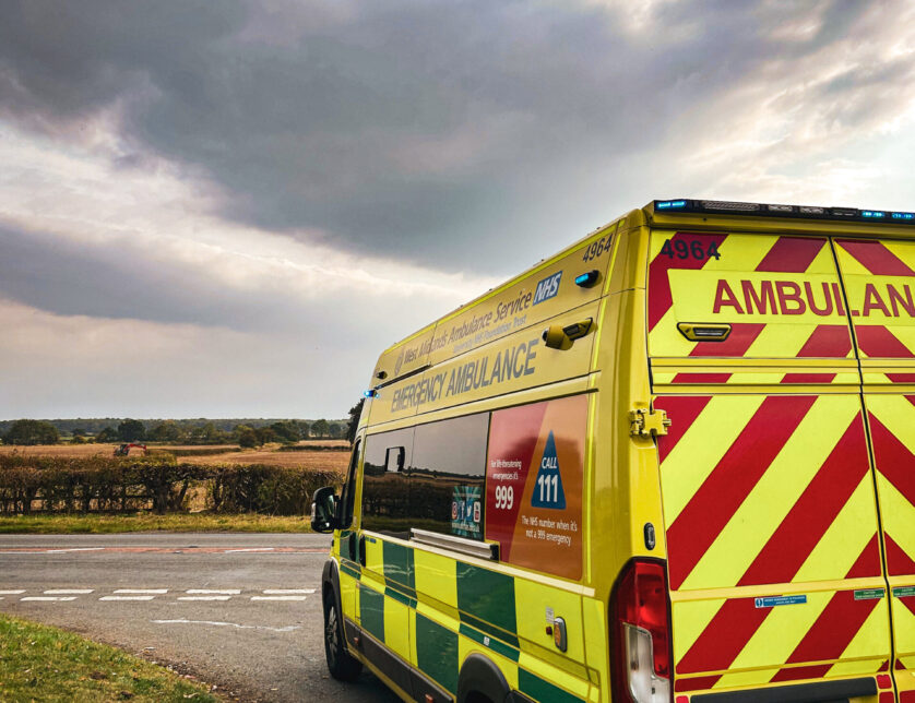 Ambulance parked up on side of rural road with countryside in distance