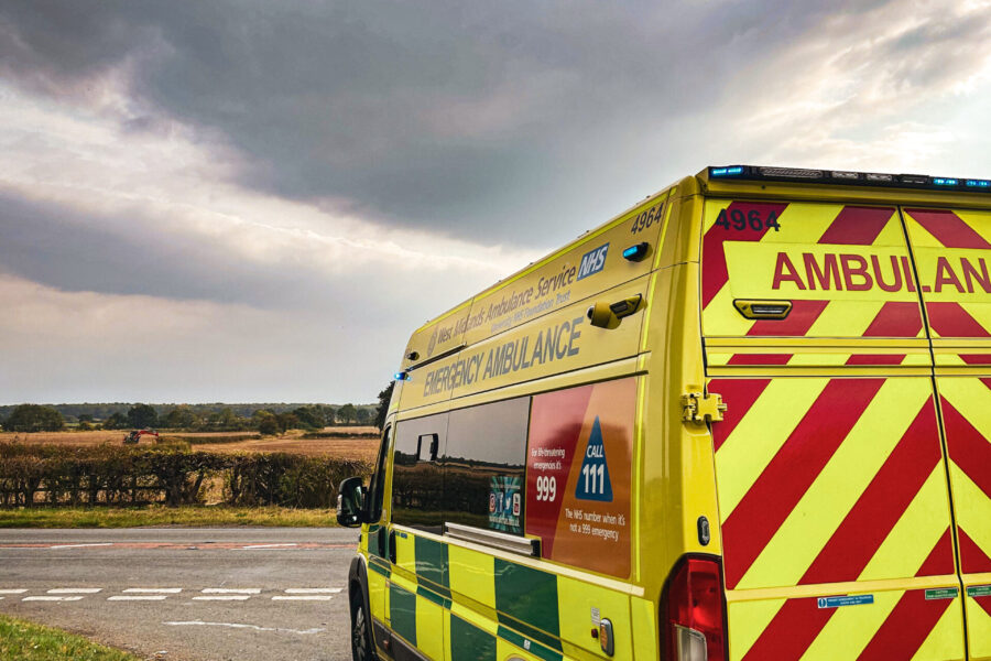 Ambulance parked up on side of rural road with countryside in distance