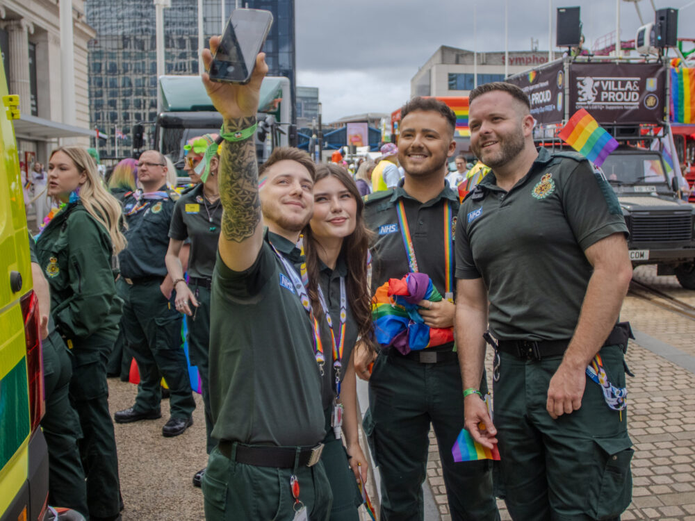 Four ambulance staff in green uniform taking selfie whilst at Birmingham Pride