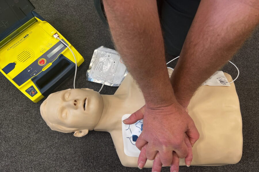 CPR being performed on a mannequin with a defibrillator attached