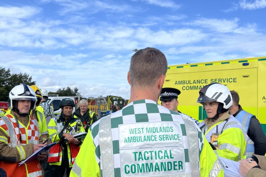 JESIP meeting at scene of major incident exercise with ambulance, police, fire and other agencies wearing high viz and helmets