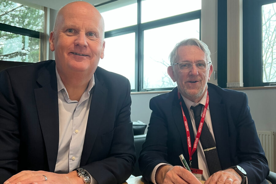 Two men sitting at a desk signing a piece of paper