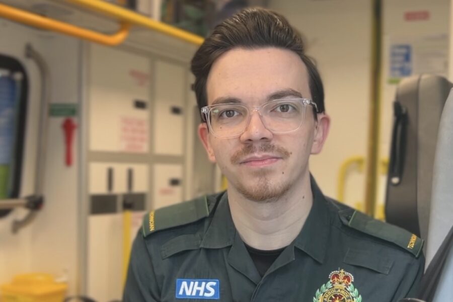 Technician (student paramedic) sitting in back of ambulance facing camera.